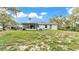 Exterior shot showing an enclosed porch and sloping backyard with lots of mature shade trees at 306 Olmo Ct, Winter Haven, FL 33880