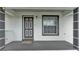Covered front porch offers an exterior light fixture, welcome mat, and neutral wall color at 306 Olmo Ct, Winter Haven, FL 33880