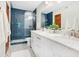 Bright bathroom features a double sink vanity, marble countertop, and blue tiled shower with glass door at 312 Palencia Pl, Lakeland, FL 33803
