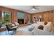 Cozy living room features a brick fireplace, wood paneling, and plush white furniture at 312 Palencia Pl, Lakeland, FL 33803