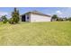 Expansive backyard showcases lush lawn extending from the home, complemented by trees and manicured landscaping at 3136 Langdon Ln, Winter Haven, FL 33884