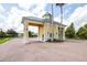 A charming gated entrance with yellow pillars, a green roof, and brick-paved road at 3136 Langdon Ln, Winter Haven, FL 33884