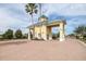 A charming gated entrance with yellow pillars, a green roof, and brick-paved road at 3136 Langdon Ln, Winter Haven, FL 33884