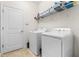 Bright laundry room features a white washer and dryer, practical shelving, and a door to the rest of the home at 3136 Langdon Ln, Winter Haven, FL 33884