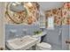 Retro blue-tiled bathroom with floral wallpaper, vanity and a decorative round mirror at 323 E Belvedere St, Lakeland, FL 33803