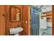 Rustic bathroom adjacent to garage with pedestal sink and wood paneled walls at 323 E Belvedere St, Lakeland, FL 33803