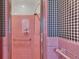 Pink tiled shower with checkered walls and a glass shower door at 323 E Belvedere St, Lakeland, FL 33803