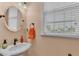 Half bath features a pedestal sink, window and bronze fixtures at 3243 Red Tail Hawk Dr, Polk City, FL 33868