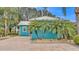 Charming blue home featuring a metal roof and mature palm trees surrounded by a brick driveway at 3243 Red Tail Hawk Dr, Polk City, FL 33868