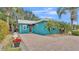 Charming turquoise home featuring a metal roof, paved driveway, and lush tropical landscaping at 3243 Red Tail Hawk Dr, Polk City, FL 33868