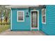 Close up of the turquoise home featuring a decorative front door and black and white striped awning at 3243 Red Tail Hawk Dr, Polk City, FL 33868