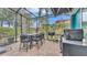 Screened patio with outdoor dining set, grill, and lush landscaping offers space for entertaining at 3243 Red Tail Hawk Dr, Polk City, FL 33868