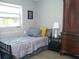 Comfortable bedroom with natural light, featuring a bed, side table, and antique armoire at 355 E Columbia St, Lake Alfred, FL 33850