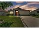Charming single-story home featuring a well-manicured lawn, two-car garage, and inviting front entrance with brick-red door at 420 Sir Phillips Dr, Davenport, FL 33837