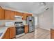 Functional kitchen with stainless steel refrigerator, tile flooring, and wood cabinets at 420 Sir Phillips Dr, Davenport, FL 33837