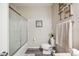Compact bathroom features a shower-tub combo with glass doors, stylish decor, and hardwood floors at 4303 Moon Shadow Loop, Mulberry, FL 33860