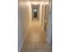Bright hallway with neutral tile flooring leads to the bathroom at the end of the hall at 5121 Shady Oak S Dr, Lakeland, FL 33810