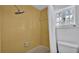 Retro yellow tiled shower and bathtub combo with white shower curtain, window and toilet at 516 Windsor St, Lakeland, FL 33803