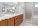 Bright bathroom featuring double sinks, wood cabinets, modern tile, and a glass shower door at 5393 Se 129Th Ln, Belleview, FL 34420