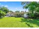 Backyard view showing lush lawn, mature shade trees, and attached carport with garage at 5425 Lewellyn Rd, Lakeland, FL 33810