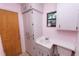 Cozy bathroom featuring pink walls, linoleum flooring, and a window for natural light at 5425 Lewellyn Rd, Lakeland, FL 33810