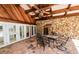 An open air patio has a stone floor, stone walls and wooden beamed roof with ceiling fan at 5425 Lewellyn Rd, Lakeland, FL 33810