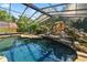 A screened in pool features a rock waterfall and clear water that reflects the sky at 5425 Lewellyn Rd, Lakeland, FL 33810