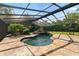 A screened in pool features a unique rock feature and is surrounded by stone flooring at 5425 Lewellyn Rd, Lakeland, FL 33810