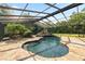 A screened in pool features a unique rock feature and is surrounded by stone flooring at 5425 Lewellyn Rd, Lakeland, FL 33810