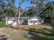 Charming single-story white home featuring a brick patio and lush landscaping beneath mature trees at 5624 Laurel Oak Dr, Lakeland, FL 33811