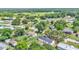 Wide aerial view of a home with a dark roof and white siding in a neighborhood dotted with mature trees and green spaces at 5751 Cherry Tree Dr, Lakeland, FL 33811