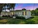 Charming single-story home with white siding, black shutters, front porch, and mature trees on a green lawn at 5751 Cherry Tree Dr, Lakeland, FL 33811