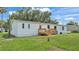 This is the rear of the home, which features a deck, green lawn, and mature trees at 5751 Cherry Tree Dr, Lakeland, FL 33811