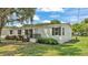 Charming single-story home featuring white siding, black shutters, and a quaint front porch nestled in a well-maintained yard at 5751 Cherry Tree Dr, Lakeland, FL 33811