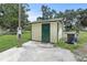 Shed featuring a green door and trim, set against a light yellow exterior with a concrete pad at 633 Glenda St, Lakeland, FL 33805