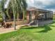 Backyard features a covered patio with seating, a pool, lush lawn, and landscaping, perfect for outdoor living at 6357 Ashley Dr, Lakeland, FL 33813