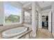 Bathroom featuring a drop-in bathtub with tile surround, separate shower, and large window at 6542 Eagle Ridge Way, Lakeland, FL 33813