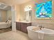 Bright bathroom with a soaking tub, dual sinks and a stained glass window at 13525 Gorgona Isle Dr, Windermere, FL 34786