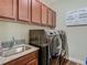 Laundry room featuring modern appliances, a granite sink, and wooden cabinets for storage at 13525 Gorgona Isle Dr, Windermere, FL 34786