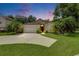 Beautiful home with lush landscaping, a two-car garage, and a red front door at dusk at 1003 Clearpointe Way, Lakeland, FL 33813
