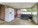 Enclosed porch with full-sized refrigerator, brick accent wall, and grill; ready for outdoor entertaining at 102 Pike St, Auburndale, FL 33823