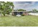 A well-maintained backyard showcasing a brick house with an enclosed porch and a lush lawn at 102 Pike St, Auburndale, FL 33823