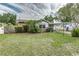 Home exterior view with a lush green lawn, mature landscaping, and a covered parking area at 102 Pike St, Auburndale, FL 33823