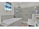 Bright bathroom featuring a soaking tub, glass enclosed shower with marble tile surround, and a privacy window at 1146 Enclave Ct., Auburndale, FL 33823
