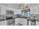 Well-lit kitchen featuring white cabinets, stainless steel appliances, and black granite countertops with a mosaic backsplash at 1423 Ridgegreen N Loop, Lakeland, FL 33809