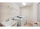 Well-lit laundry room featuring a utility sink, tile flooring, washer, dryer, and white wire shelving at 188 Morning Dew Ct, Winter Haven, FL 33884