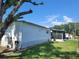 View of the home's exterior, showing the screened-in porch, well-kept lawn, and mature trees at 2005 Blue Lake Dr, Lakeland, FL 33801