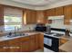 Well-lit kitchen with wood cabinets, laminate countertops, gas range and stainless steel sink at 2005 Blue Lake Dr, Lakeland, FL 33801