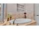 Soaking tub and decoratively tiled walls with glass shelf inserts, with glass enclosed shower to the left at 2025 Viewpoint Landings Rd, Lakeland, FL 33810