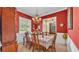 Formal dining room with red walls, traditional chandelier, and view into the living room at 2025 Viewpoint Landings Rd, Lakeland, FL 33810
